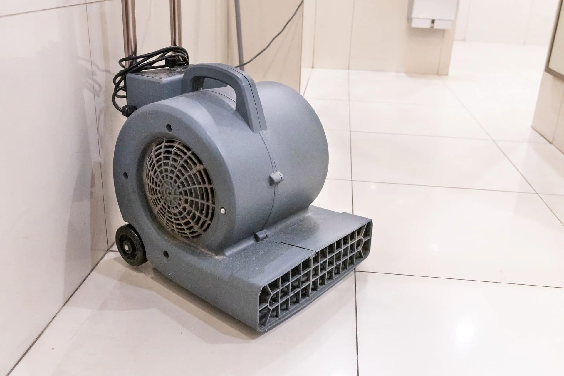 Air mover drying a white tile floor