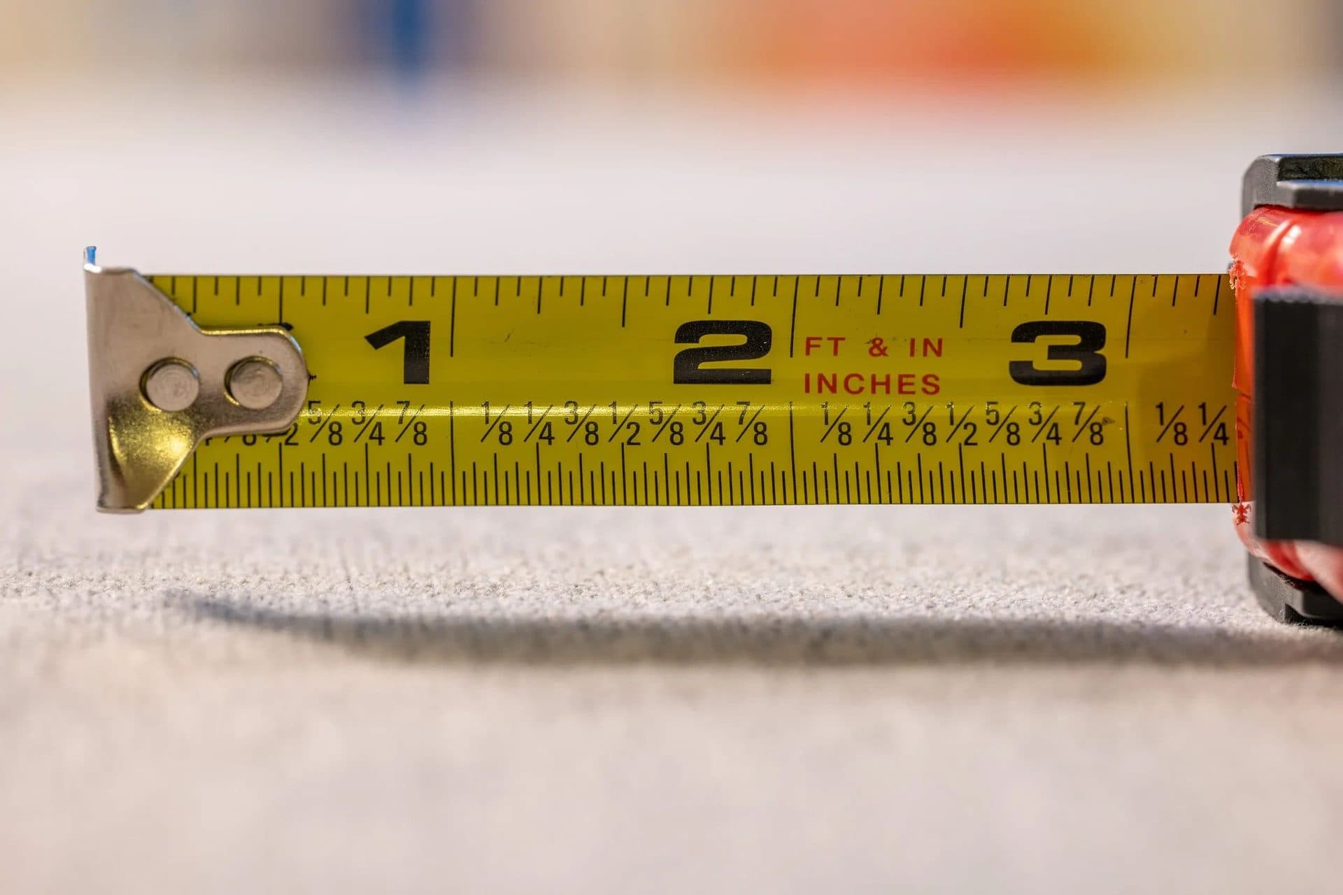 Tape measure extended across carpet during a measured estimate