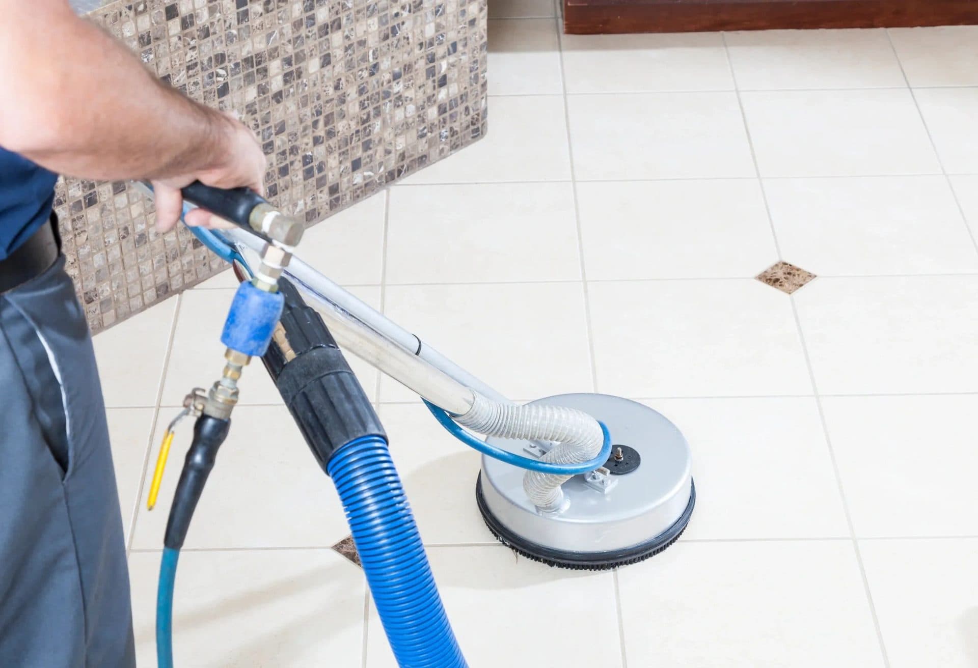 Technician running a spinner extraction tool over a tile floor and grout lines