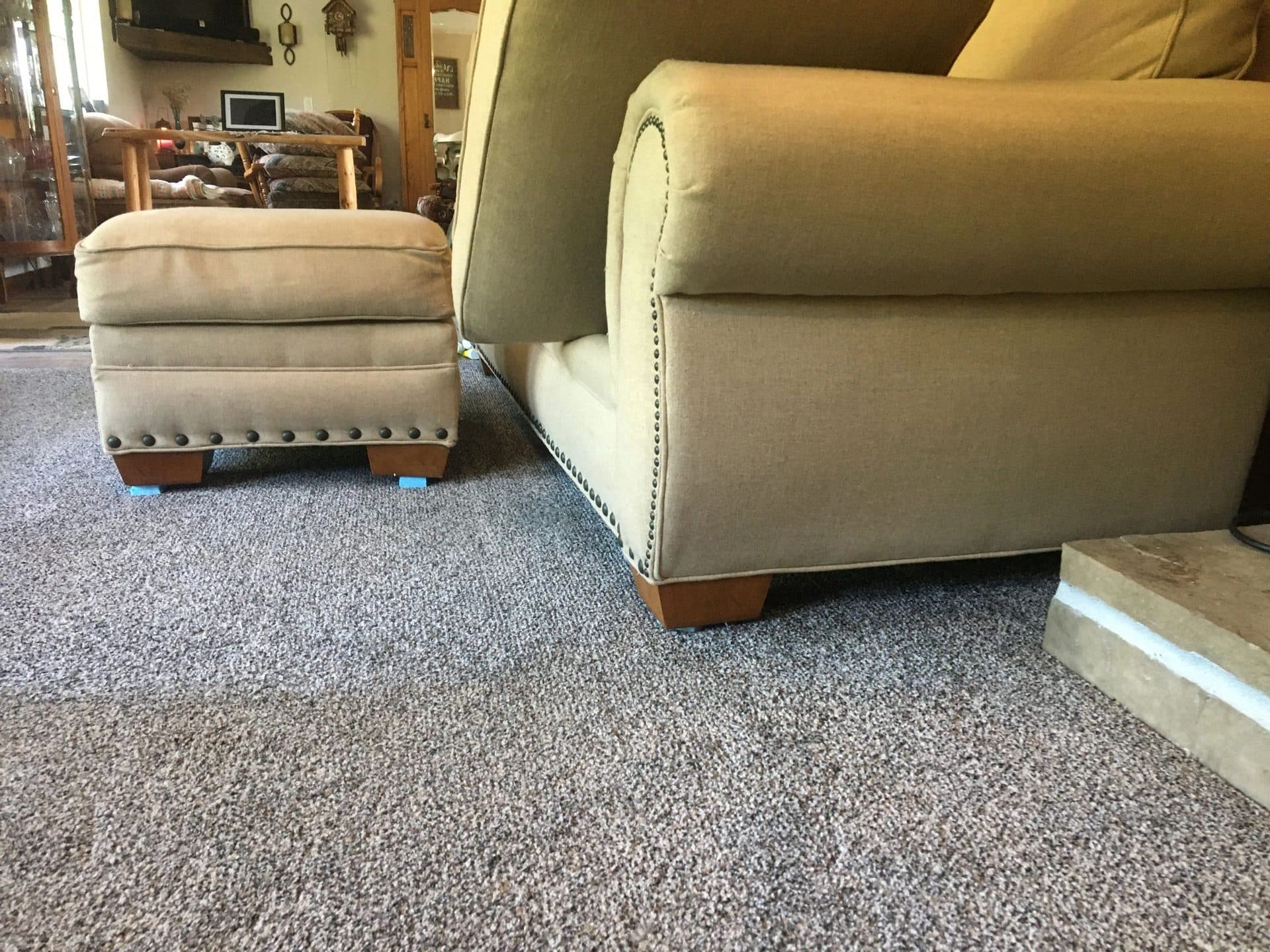 Tan upholstered chair and matching ottoman with nailhead trim